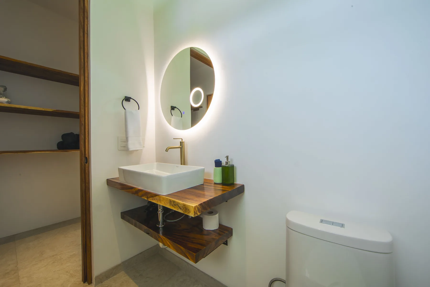 Ensuite bathroom with stone wall and round mirror at Villa Amara